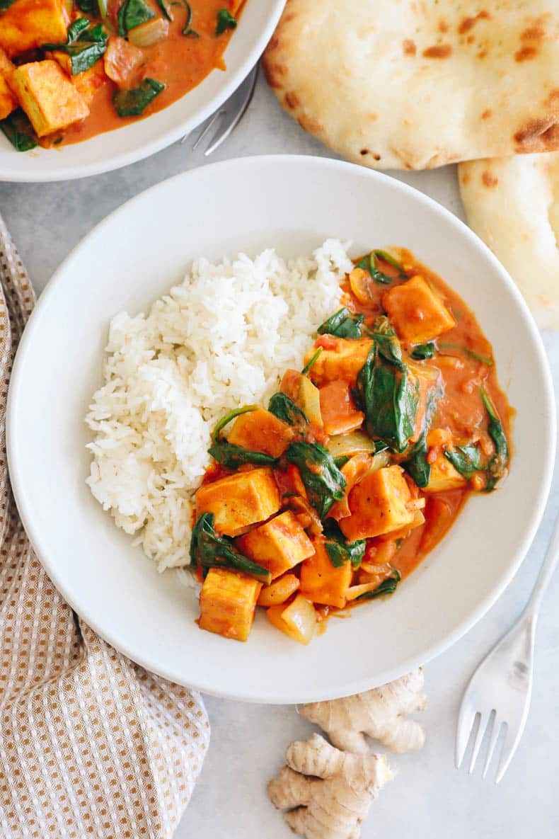 overhead photo of yellow tofu curry with rice in a white bowl.