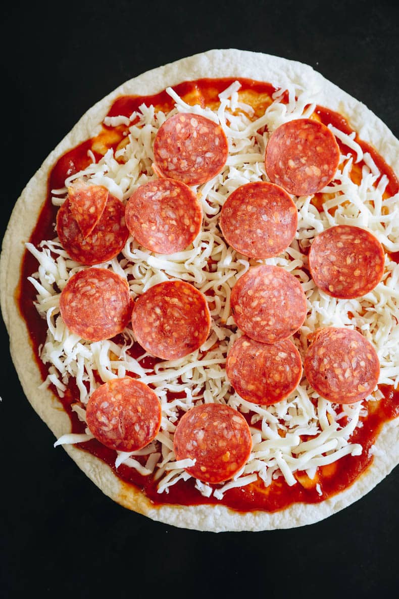 unbaked tortilla pizza on a baking sheet