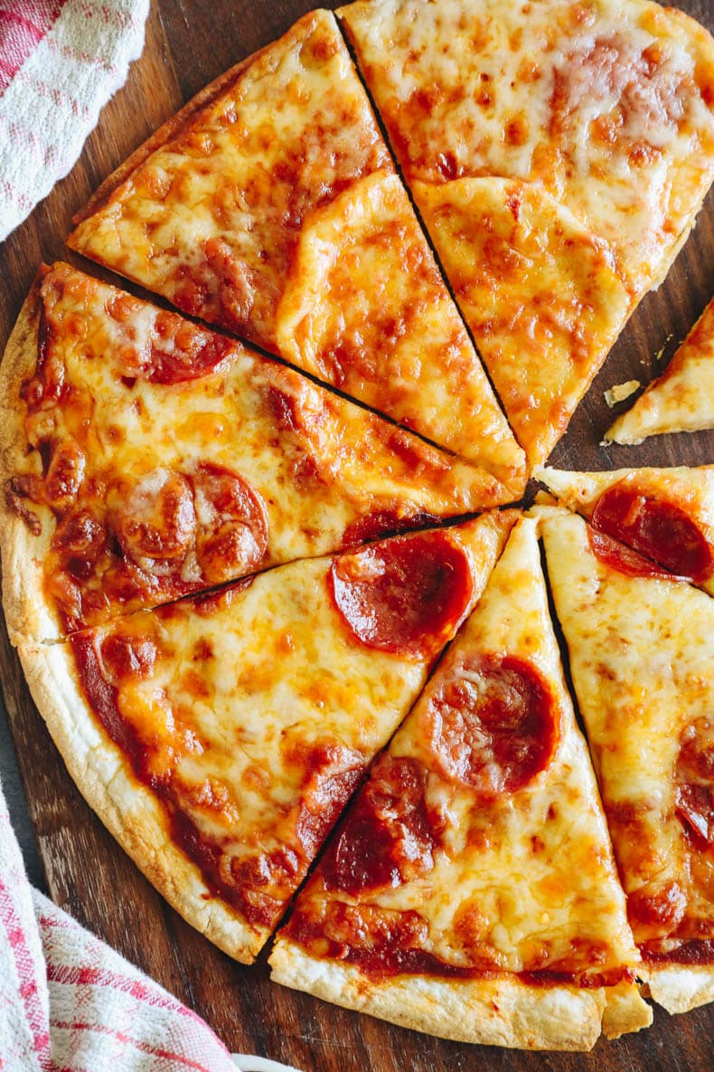 Baked tortilla pizza with pepperoni on a cutting board.