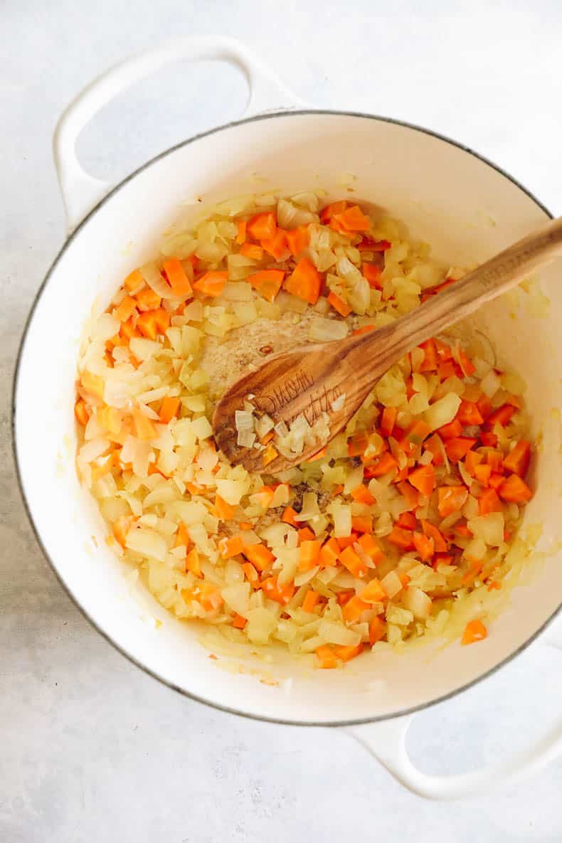 cooked onion, garlic and carrots in a white dutch oven for turkey bolognese