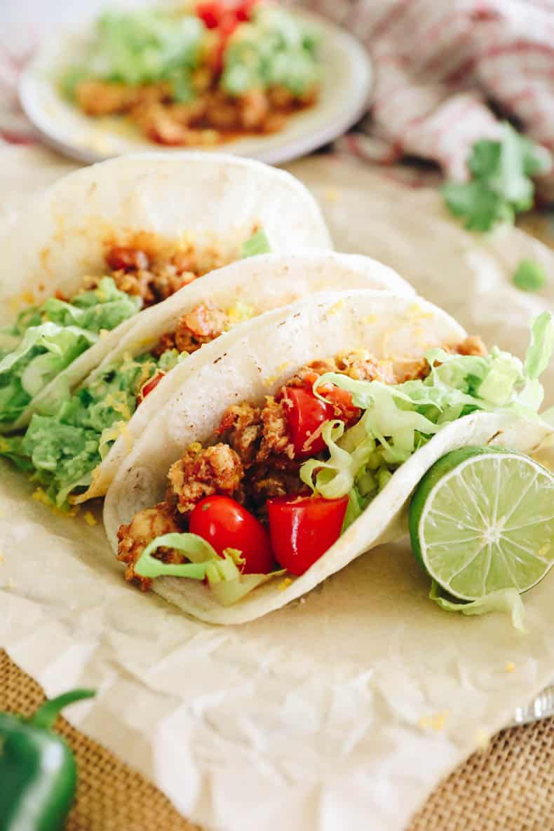 turkey tacos lined up on a parchment lined plate.