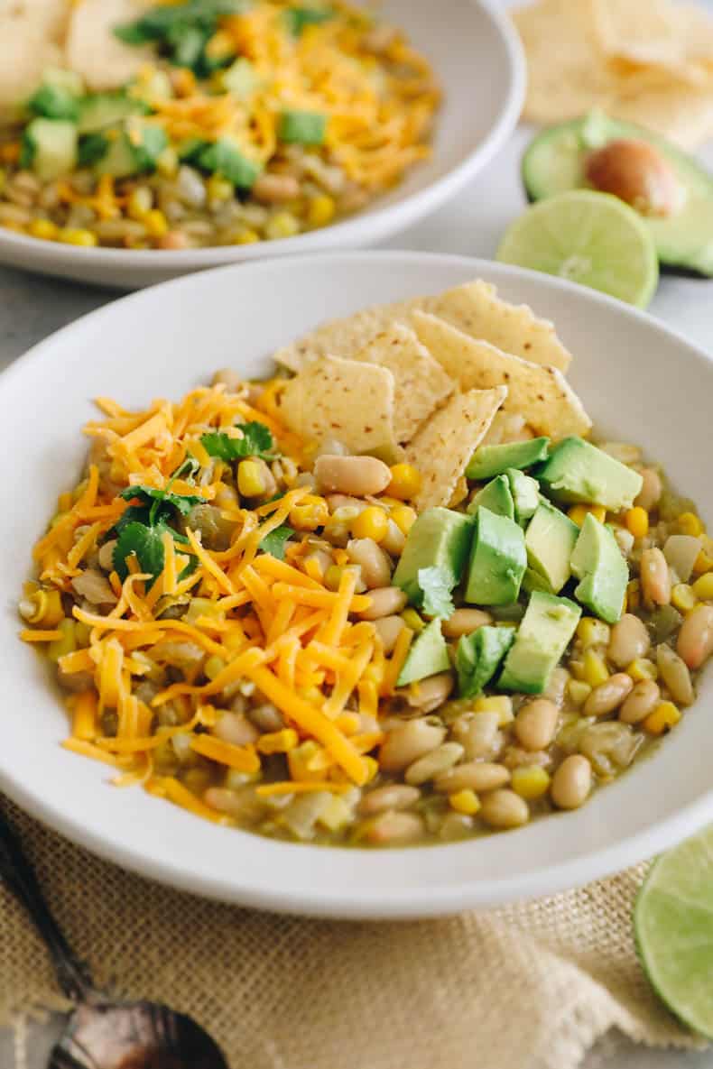 white bean chili in a white bowl topped with chili toppings.