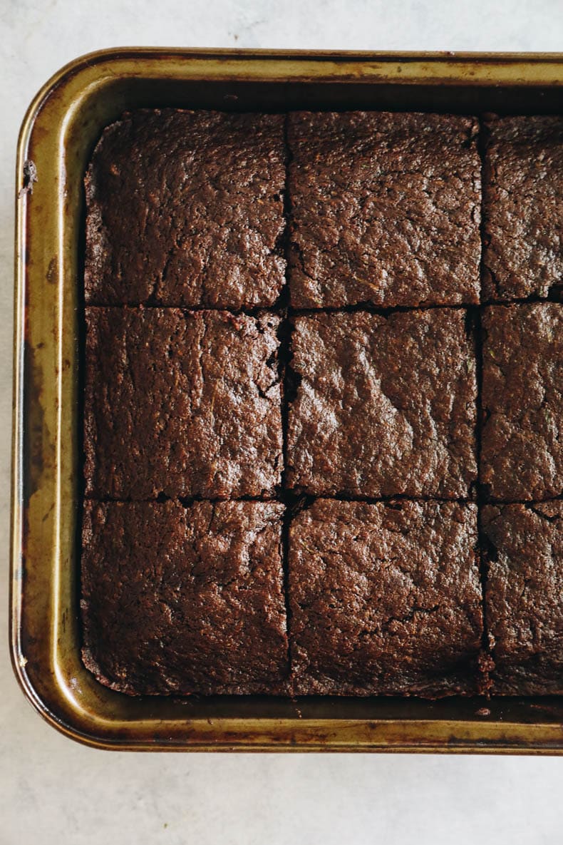 zucchini brownies cut into 9 squares in a baking pan.