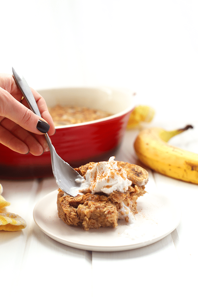 A spoon scooping up some baking oatmeal on a white plate.